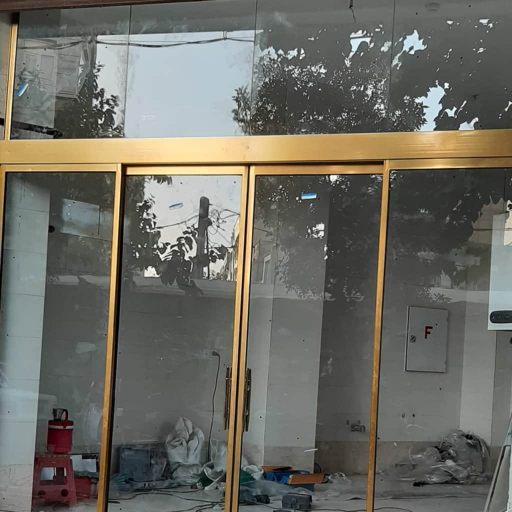 درب اتوماتیک شیشه ای ورودی فروشگاه با رنگ فریم هماهنگ نما
